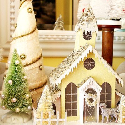 Yellow glitter house as part of a glitter house village Christmas mantel display.