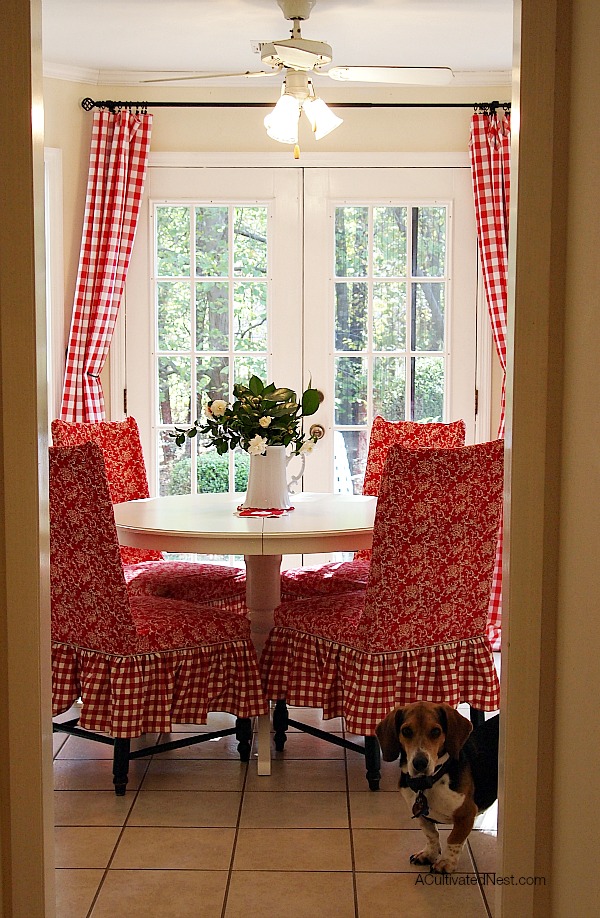 Pretty red and white dining room! Red buffalo check curtains, Ikea Liatorp dining table, red slipcovered chairs