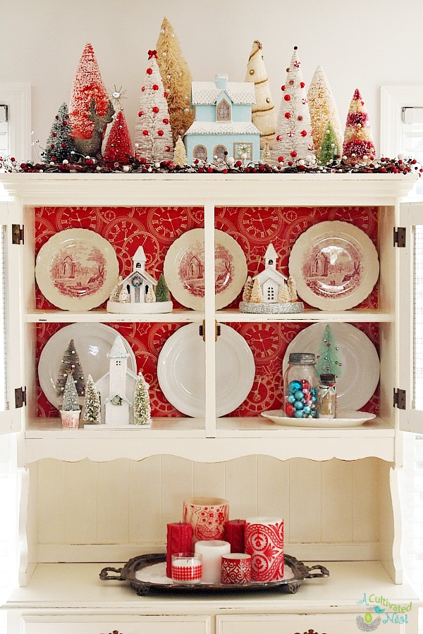 Super cute china cabinet decorated for Christmas. Lots of bottle brush trees, glitter houses  and lots of aqua and red!