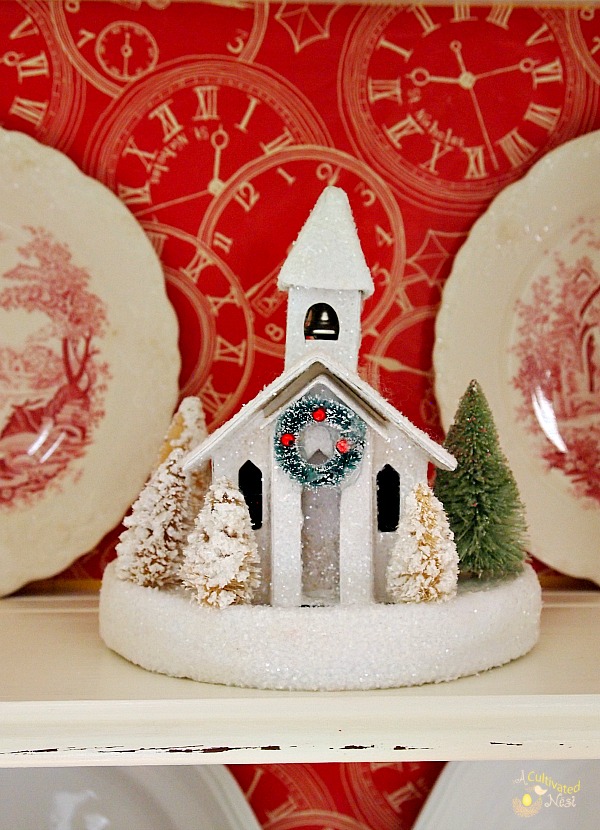 Cute Christmas china cabinet!  Church glitter house and red and white transferware on this shelf.