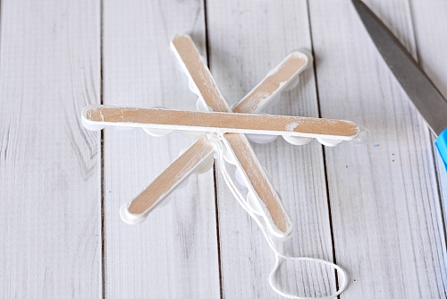 Popsicle Stick Button Snowflake- This homemade Christmas tree ornament is so fun to make, and easy to customize! This year, add this cute DIY popsicle stick button snowflake to your tree! | diy Christmas ornament, Christmas craft, homemade Christmas ornament ideas
