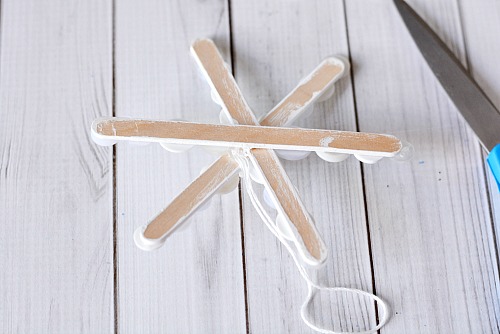 Popsicle Stick Button Sneeuwvlok - Dit zelfgemaakte kerstboomornament is zo leuk om te maken en gemakkelijk aan te passen!  Voeg dit jaar deze schattige DIY-ijslollyknop-sneeuwvlok toe aan je boom!  |  diy kerstornament, kerstknutselen, zelfgemaakte kerstornamentideeën