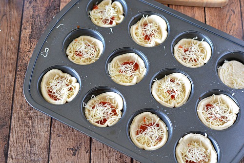 Mini Pizza Muffin Tin Appetizers- These mini pizza muffin tin appetizers are quick and easy to make, but have the flavor of a full-sized pizza! They'd make a good after-school snack, too! | New Year's Eve appetizer, New Year's recipe, party food, after-school snack, finger food, pizza bites, easy recipe