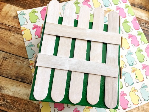 DIY Picket Fence Easter Basket- Why settle for a boring, traditional store-bought Easter basket when you can easily make this DIY picket fence Easter basket that your kids will love! | DIY project, craft idea, Easter gift basket, spring, easy DIY, inexpensive craft